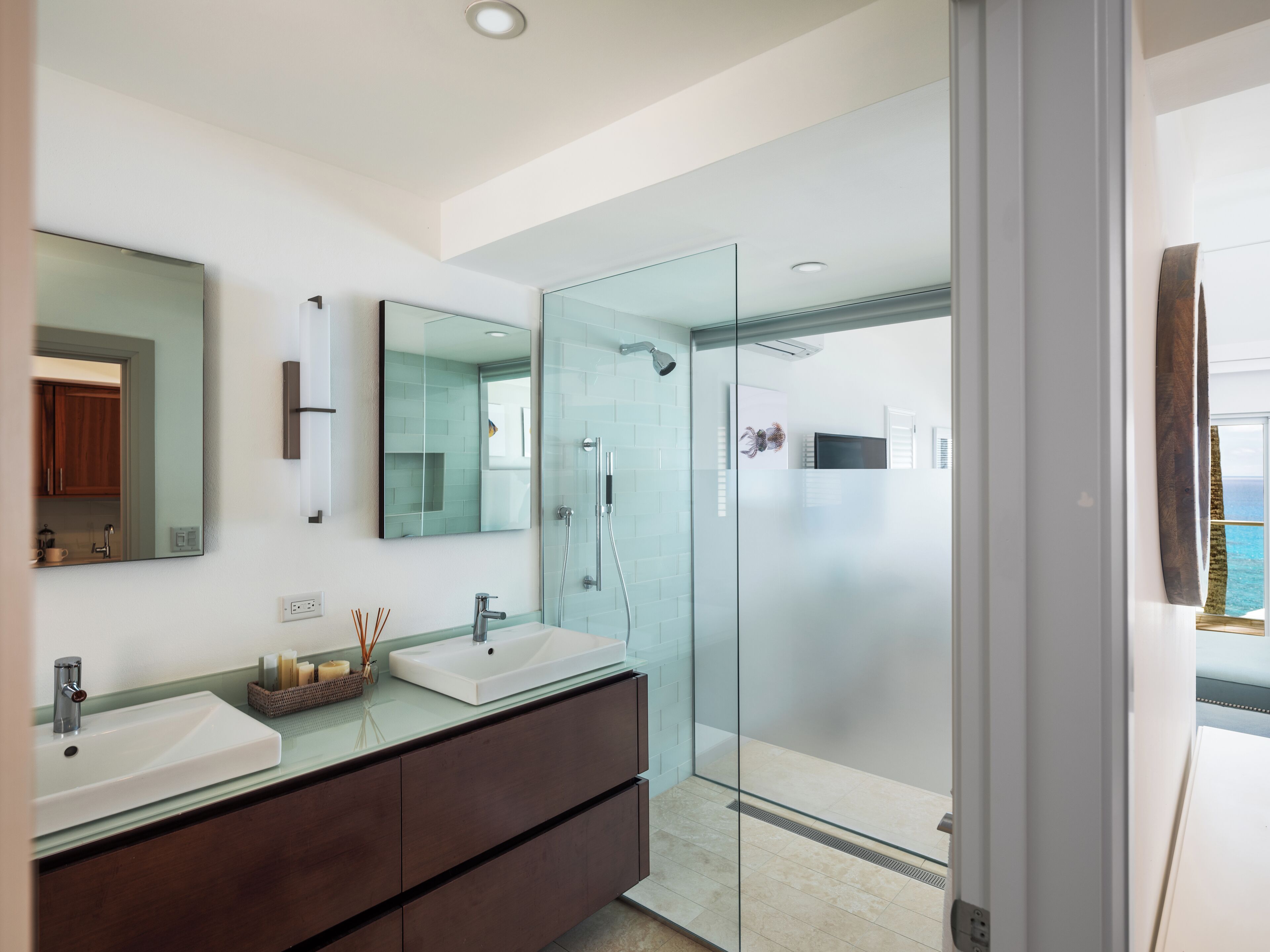 A modern bathroom with two sinks, a glass shower enclosure, and a large mirror.
