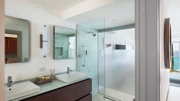 A modern bathroom with two sinks, a glass shower enclosure, and a large mirror.