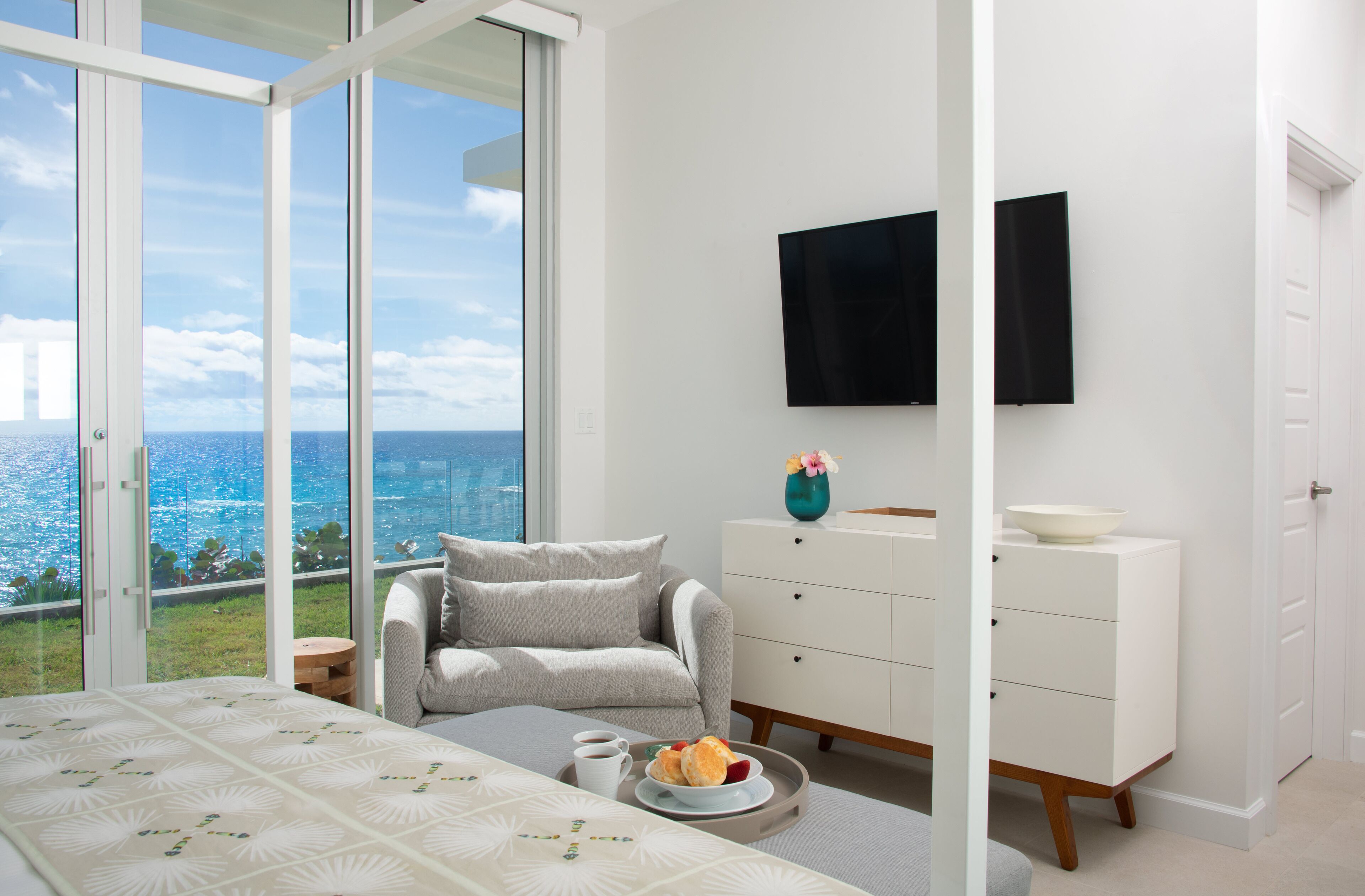 Un dormitorio moderno con una cama grande, un sofá, un aparador y un televisor.