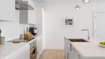 A modern kitchen with white cabinetry, a stainless steel range hood, a double sink, and pendant lighting.