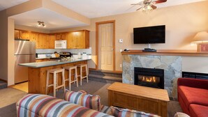 A modern kitchen with wooden cabinets, a stainless steel refrigerator, and a bar area with stools.