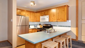 A modern kitchen with wooden cabinets, stainless steel appliances, and a light blue countertop.