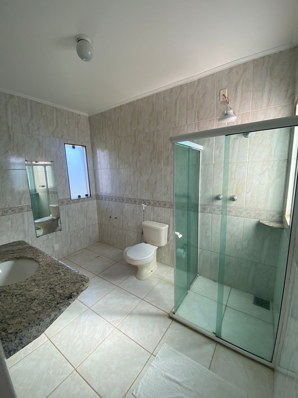 Ein Badezimmer mit Duschkabine, Toilette, Waschbecken und Spiegel.