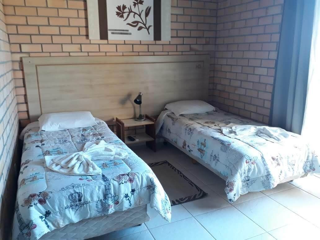 Ein Zimmer mit zwei Betten, einem Nachttisch, einer Lampe und einem gerahmten Bild an der Wand.