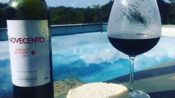 A bottle of Novecento Cabernet Sauvignon 2017 and a glass of red wine on a table with a pool in the background.