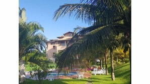 A pool area with lounge chairs, a clear sky, and a building in the background. - Pousada Herva Doce (Rio das Ostras)