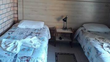 A room with two beds, a nightstand, a lamp, and a decorative wall piece.