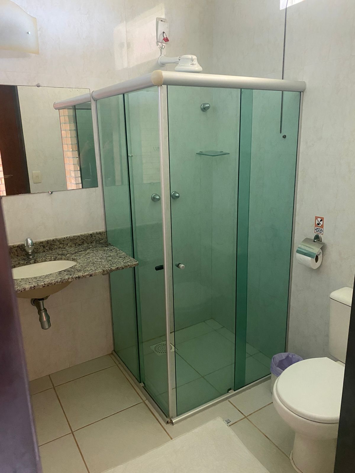Une salle de bain avec une douche à parois de verre, un lavabo doté d’un plan de travail en granit et des toilettes.