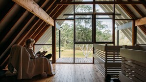 Ein Zimmer mit schrägen Wänden, großen Fenstern und Holzboden.