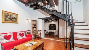 Una sala de estar con un sofá rojo, una mesa de centro de madera y una escalera con barandas negras.