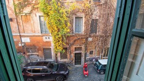 Una calle estrecha con coches aparcados y un edificio con muros cubiertos de hiedra.