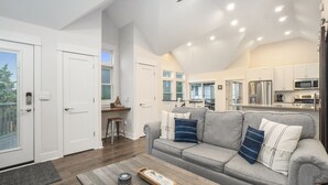 A modern kitchen with stainless steel appliances, a grey sofa with decorative pillows, and a wooden coffee table. - "Let it B" Luxury lake home in South Haven MI. Just steps to N beach. Sleeps 8. (South Haven)