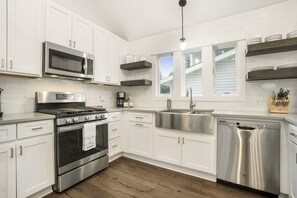 Enjoy cooking in this well-equipped kitchen with stainless steel appliances, white cabinetry, and a large sink.