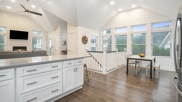 A spacious kitchen with white cabinetry, a large island, and a dining area with a table and chairs. - "Let it B" Luxury lake home in South Haven MI. Just steps to N beach. Sleeps 8. (South Haven)