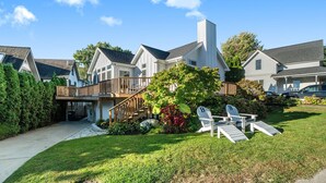 A residential house with a deck, a staircase, and a well-maintained lawn with outdoor furniture. - "Let it B" Luxury lake home in South Haven MI. Just steps to N beach. Sleeps 8. (South Haven)