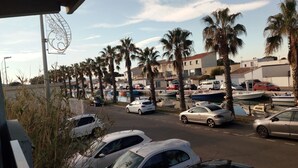 A parking area with multiple cars and boats, surrounded by palm trees and buildings.