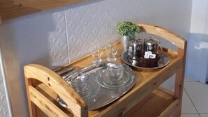 A wooden chair with a tray table, a small potted plant, and a metal tray with a teapot and cups. - Pousada São Miguel (Juazeiro do Norte)