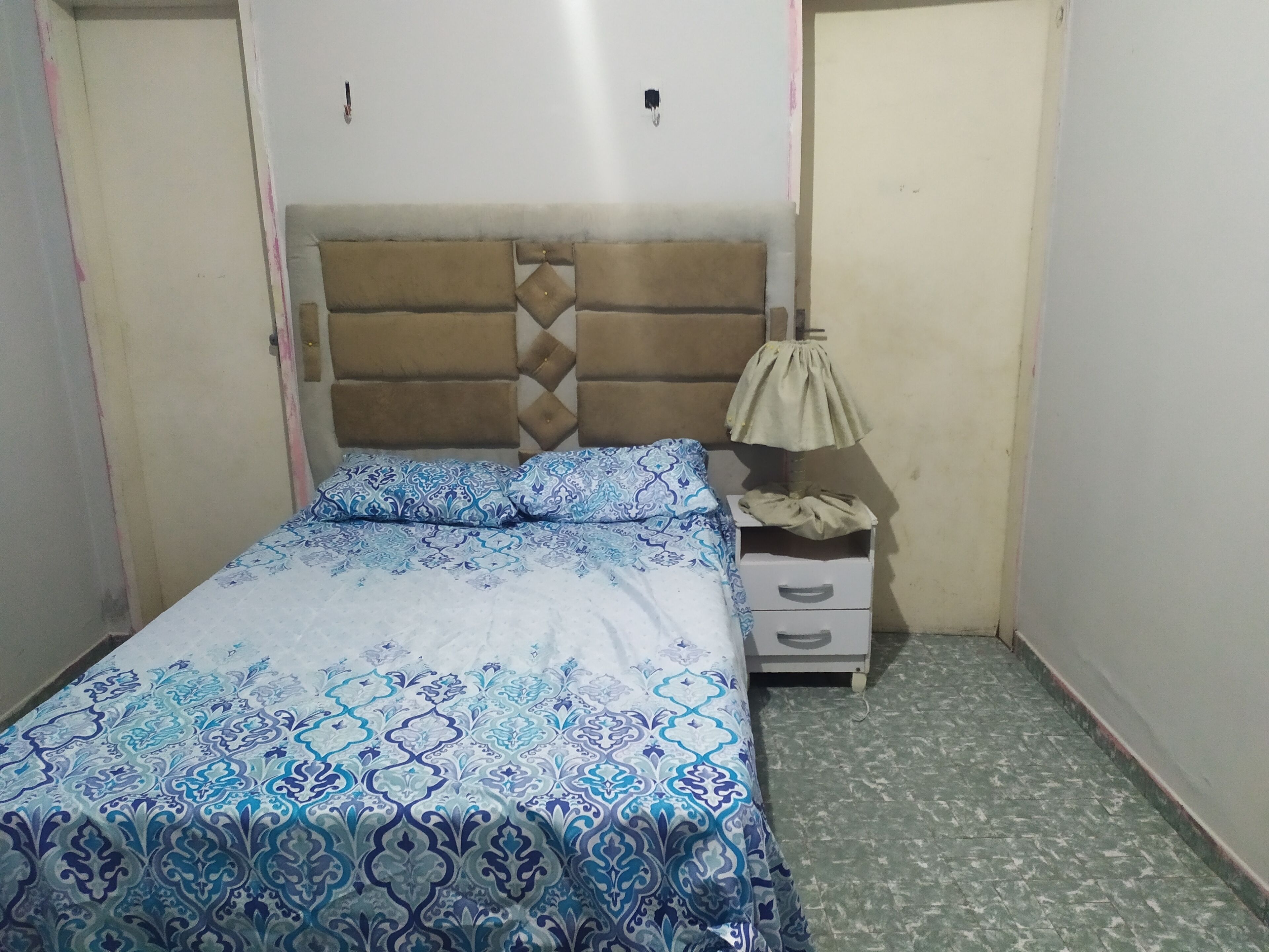 A small, neatly arranged bedroom with a bed, a bedside table, and a wardrobe.