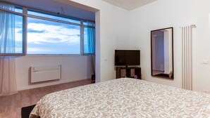 A bedroom with a large bed, a TV, a radiator, and a window with curtains. - SUPER SEA VIEW PENTHOUSE (Rimini)
