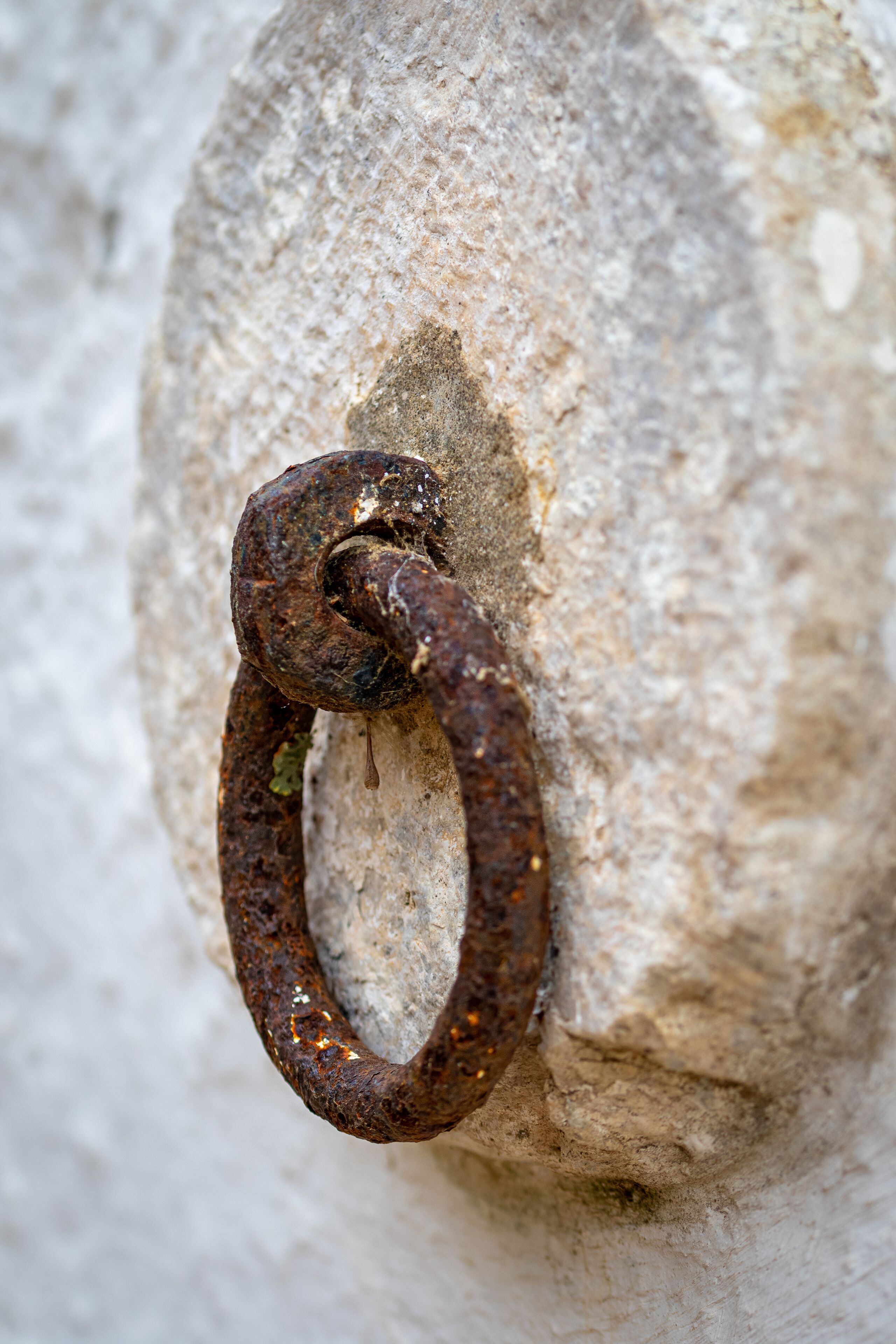 A close-up of a rusty metal ring attached to a stone surface.