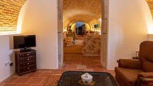 An arched doorway leading to a living room with a television, a sofa, and a coffee table. - Quinta da Foz (Caldas da Rainha)