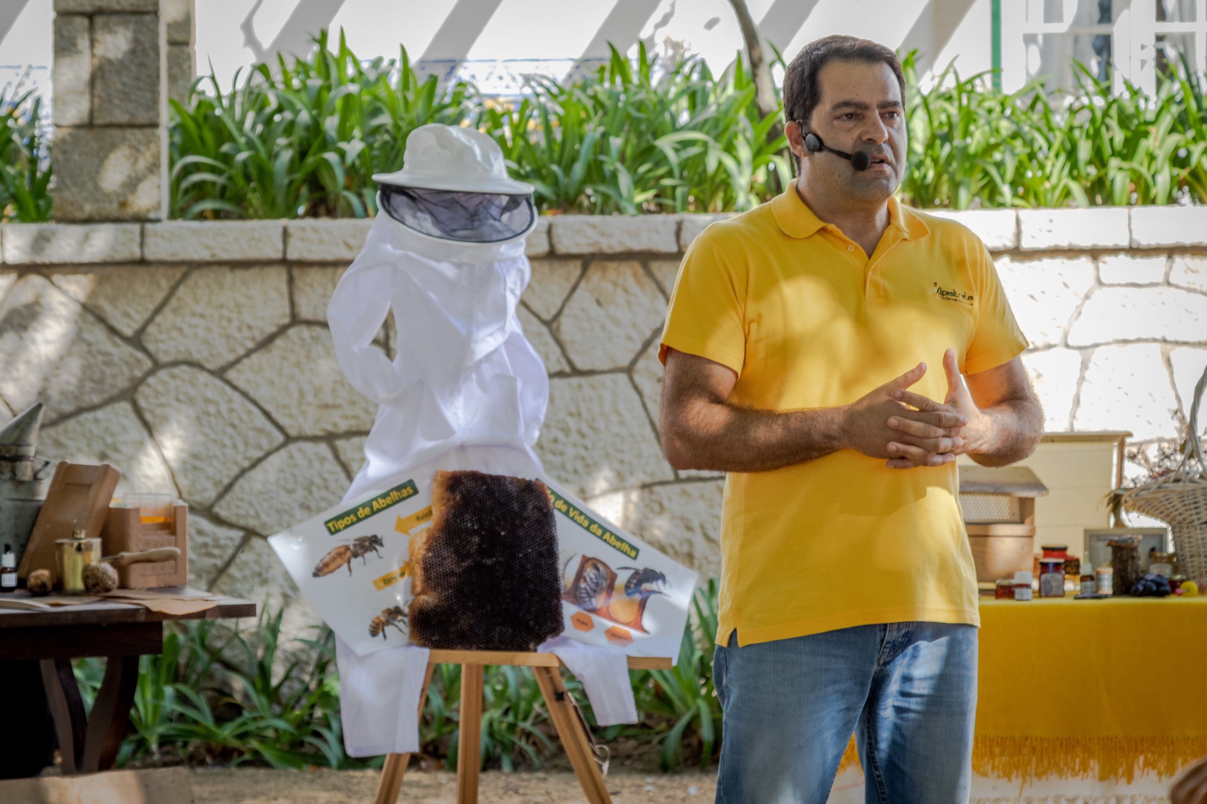 A man in a yellow shirt presenting in front of a display with a poster about types of ants.