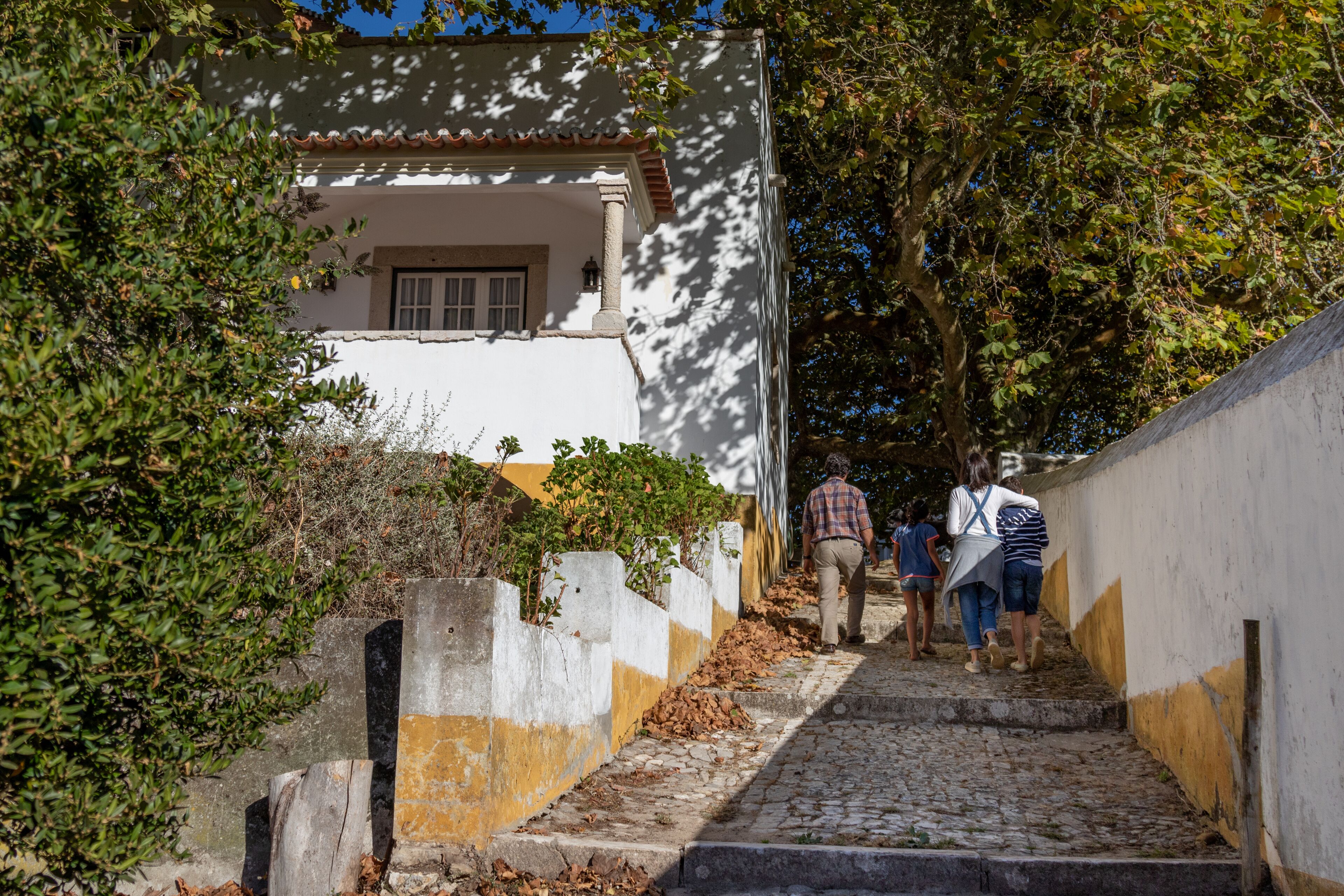 A cobblestone staircase leading up to a building with a white facade and a tiled roof.