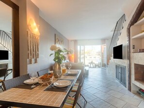 Enjoy meals in this stylish dining area with a long table, vase, bread basket, and pitcher of juice.