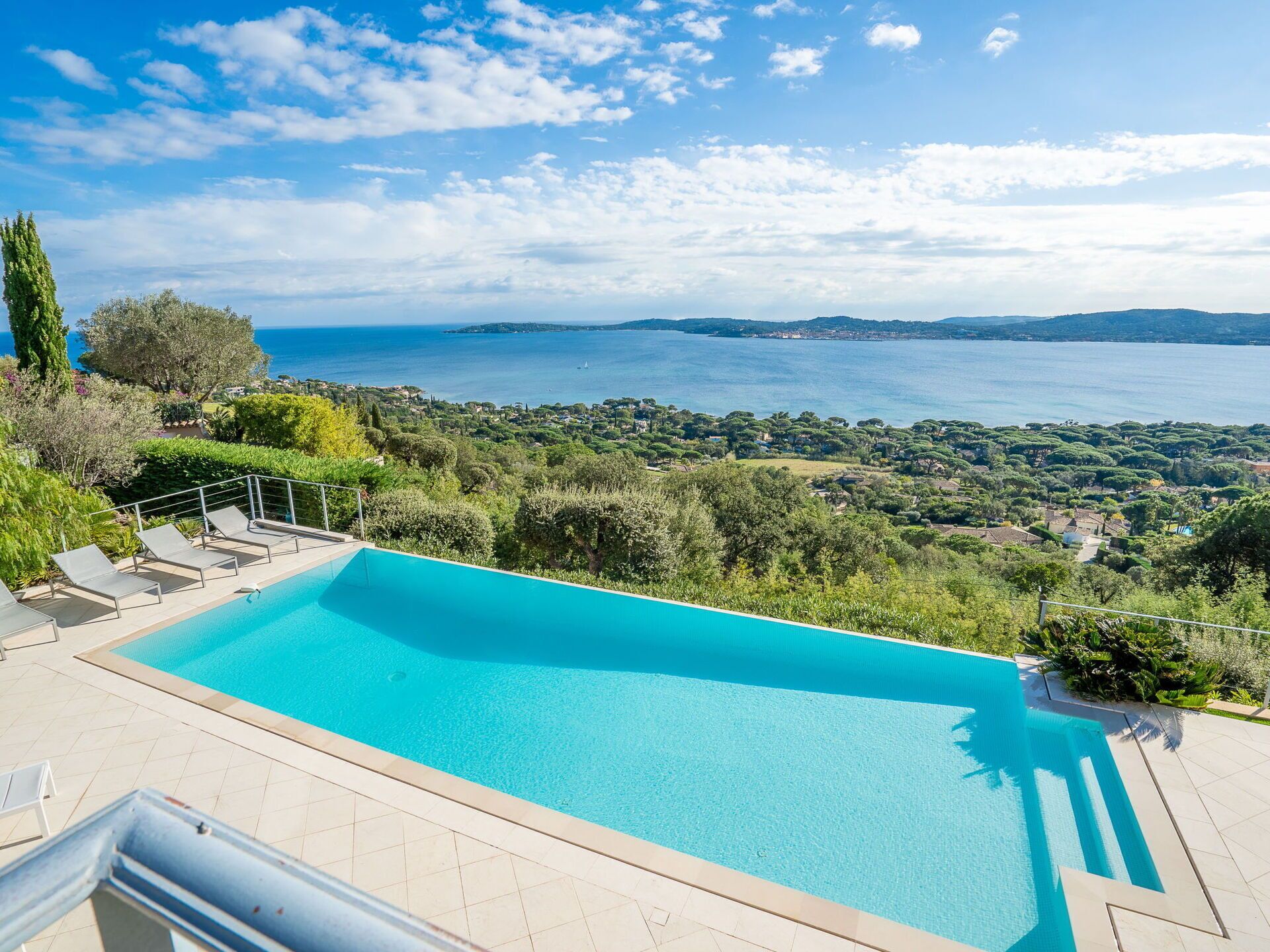 Ein Pool mit Blick auf das Meer und umliegende Grün.