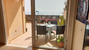 A balcony with a table and chairs, a cactus, and a view of the sea. - Nice new Duplex with big terraces, whith very nice seaviews. For your relax (Porís de Abona)
