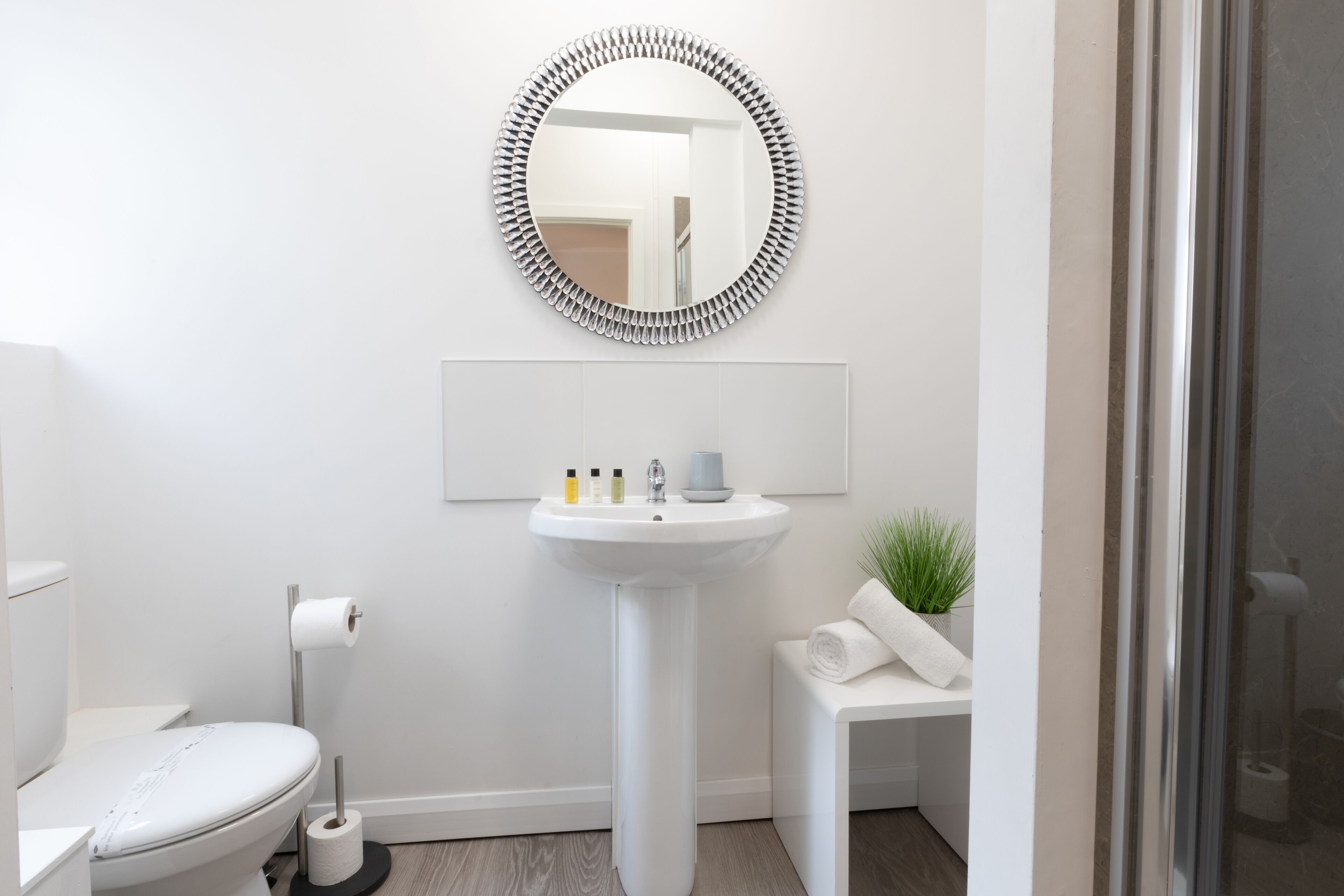 A bathroom with a white sink, toilet, and a mirror with a decorative frame.