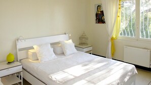 Een slaapkamer met een bed, nachtkastjes, een raam met gordijnen en een radiator.