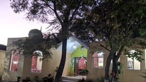 A house with a front porch, a pathway leading to the entrance, and a small garden area with potted plants. - Casa Jacarandas Chalet with Garden in Chapala (Chapala Haciendas)