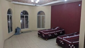 A room with two beds, a red wall, and a tiled floor. - Casa Jacarandas Chalet with Garden in Chapala (Chapala Haciendas)