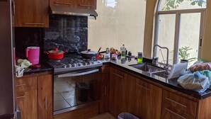 A kitchen with wooden cabinets, a stove, and a window. - Casa Jacarandas Chalet with Garden in Chapala (Chapala Haciendas)