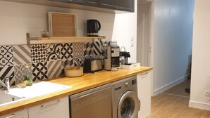 Een praktische keuken met een vaatwasser, wasmachine en koffiezetapparaat op het aanrecht.