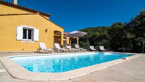 A swimming pool with lounge chairs and umbrellas, surrounded by a tiled patio and a yellow building with white shutters. - Wonderful private villa for 6 people with A/C, private pool, WIFI, TV and terrace (Lorgues)