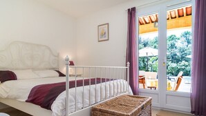 A bedroom with a bed, a wicker side table, and a view of the outdoors through a glass door. - Wonderful private villa for 6 people with A/C, private pool, WIFI, TV and terrace (Lorgues)