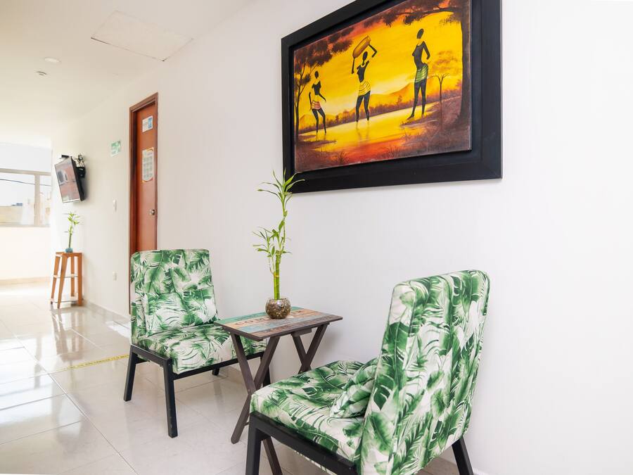 Un hall d’hôtel avec deux fauteuils, une table, un tableau et une plante en bambou.