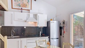A kitchen with white cabinets, a black countertop, a white refrigerator, and a dining table set for four.