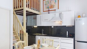 A modern kitchen with white cabinets, a black countertop, and a dining area with a glass table and chairs.