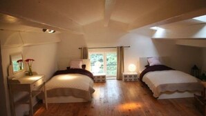 Ein Schlafzimmer mit zwei Betten, einem Schreibtisch und einem Fenster mit Vorhängen.