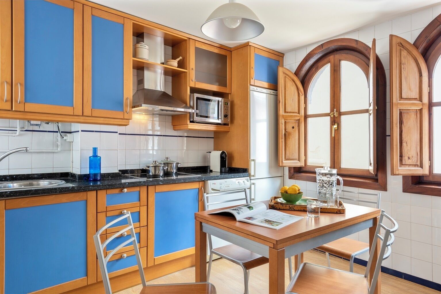 Una cucina con mobili in legno, un fornello, un forno a microonde e una finestra con persiane di legno.