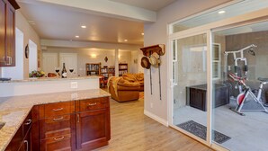 A spacious living area with a kitchen, a glass door leading to a balcony, and a home gym.
