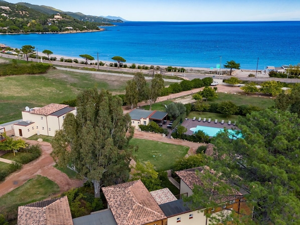 A coastal property with a swimming pool, multiple buildings, and a view of the sea.
