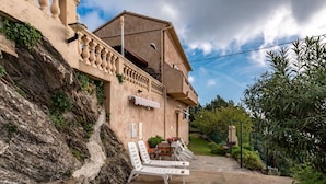 A building with a balcony, outdoor seating, and a garden area.