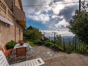 Un patio con una mesa y sillas, un camino de piedra y vistas al paisaje.