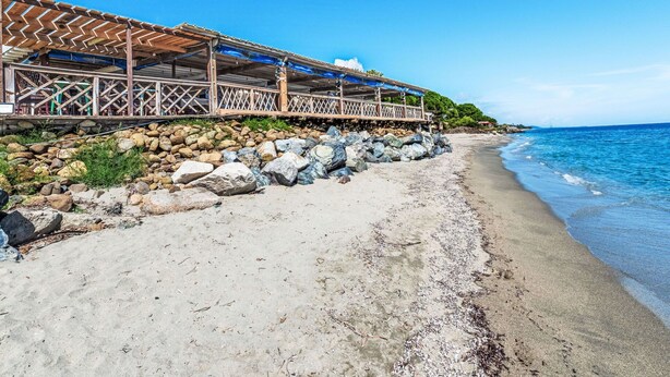 A beachside restaurant with a wooden deck and a view of the ocean.