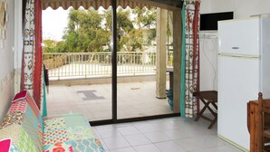 A room with a bed, a wooden chair, a white refrigerator, and a balcony with a metal railing. - Lovely apartment for 4 people with WIFI, pool, A/C, TV, terrace and pets allowed (L'Île-rousse)