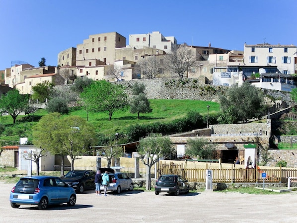 A parking area with several cars and a building with multiple windows and balconies in the background.